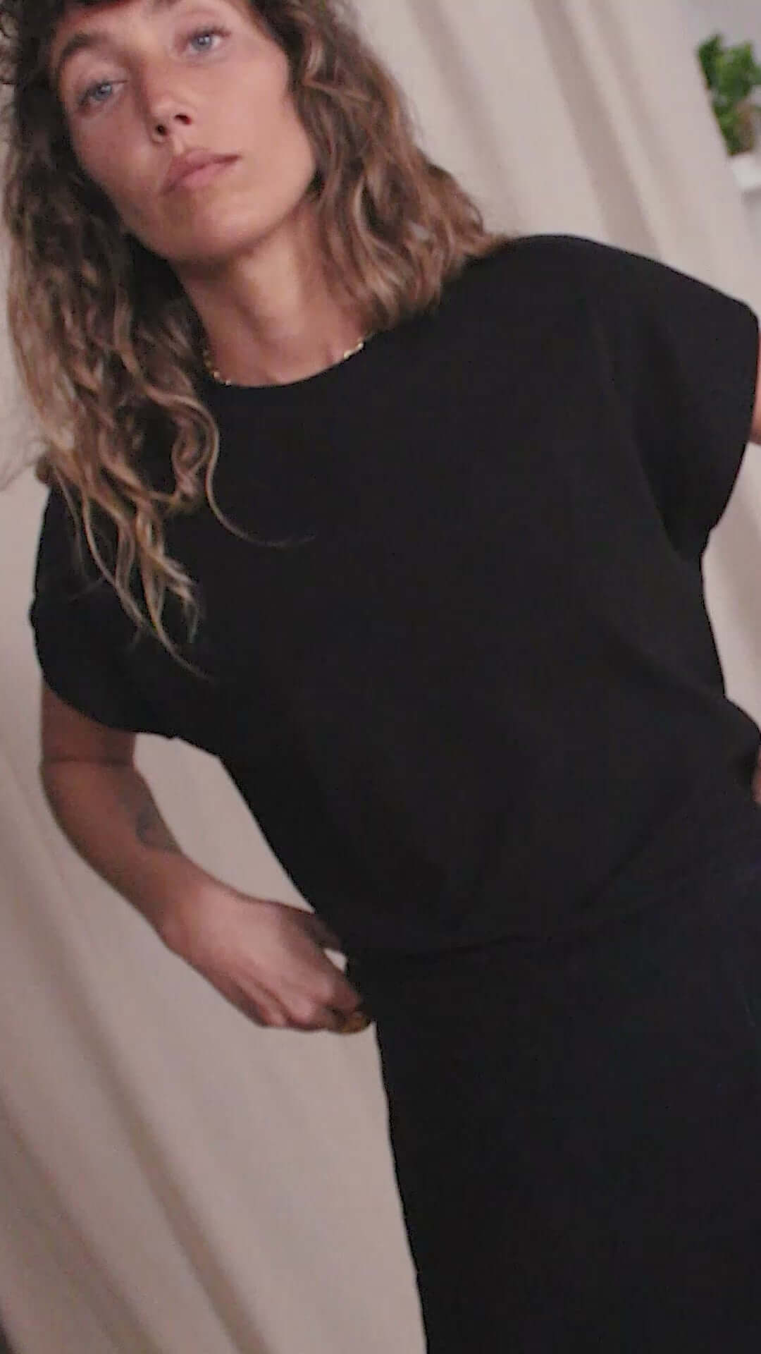 Woman wearing a black organic cotton basic tee with short cap sleeves, showcasing minimalist style and sustainability.