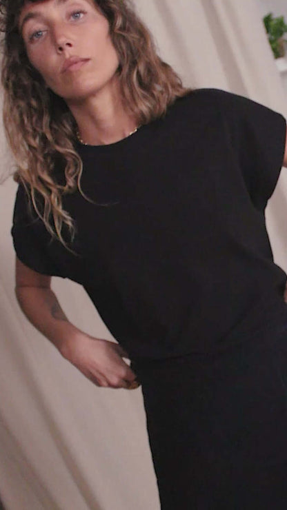 Woman wearing a black organic cotton basic tee with short cap sleeves, showcasing minimalist style and sustainability.