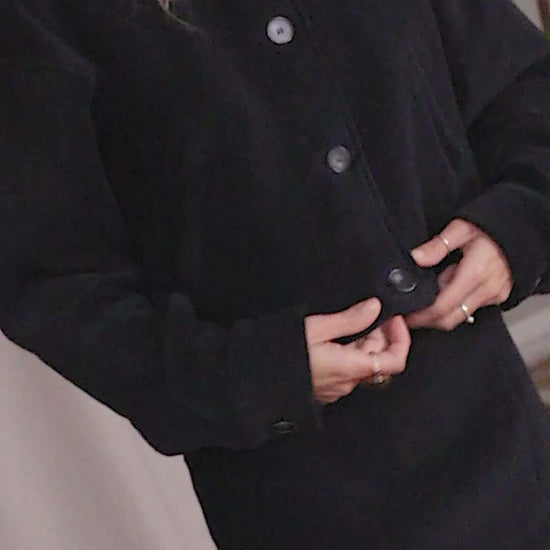 Model wearing a black organic cotton crop jacket with eco buttons, showcasing a stylish bomber-inspired design.