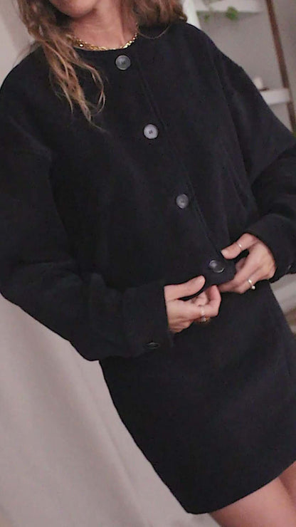 Model wearing a black organic cotton crop jacket with eco buttons, showcasing a stylish bomber-inspired design.