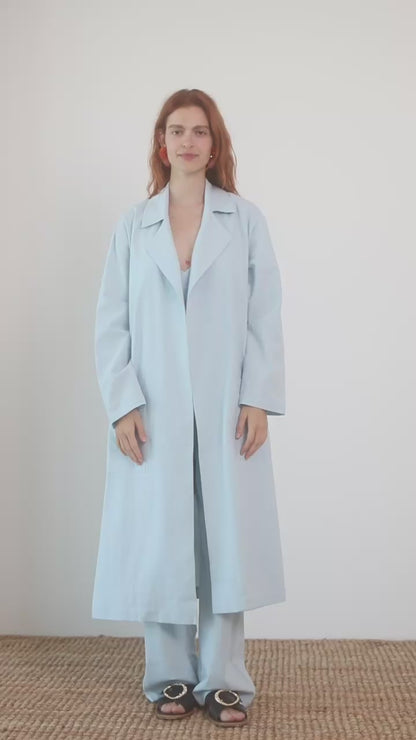 Organic Cotton Wide Jumpsuit in Pale Blue worn with a light coat, showcasing a relaxed and stylish warm-weather look.