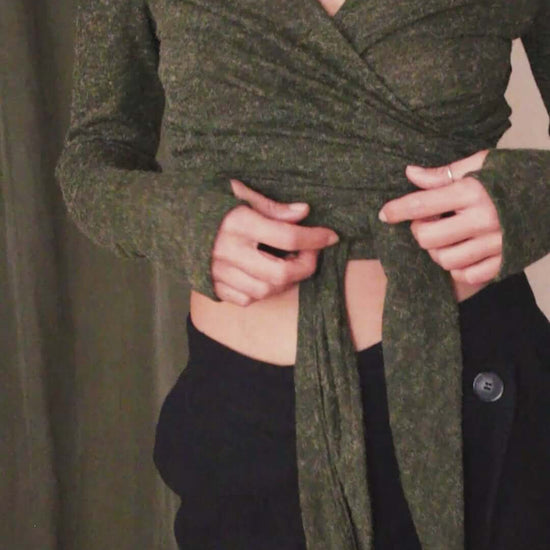 Model wearing a khaki multiway recycled jersey wrap top with thumb holes, showcasing its versatile styling options.