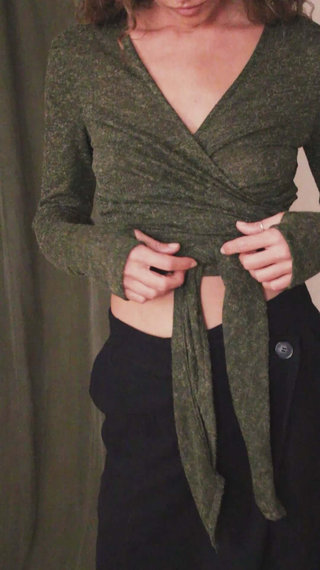 Model wearing a khaki multiway recycled jersey wrap top with thumb holes, showcasing its versatile styling options.
