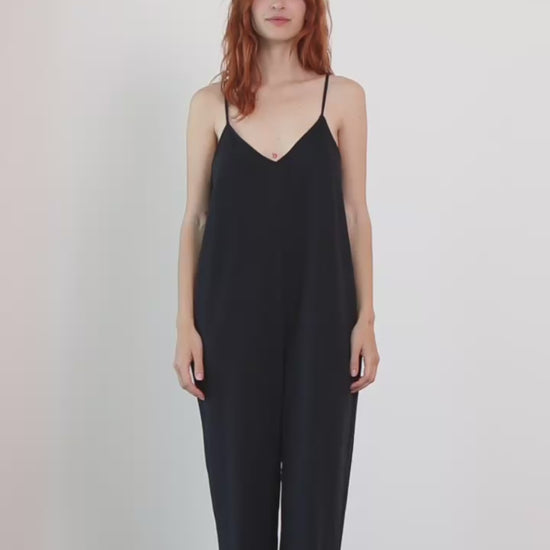 Wide Organic Cotton Strappy Jumpsuit in Black worn by a model, showcasing a relaxed silhouette and slim straps.