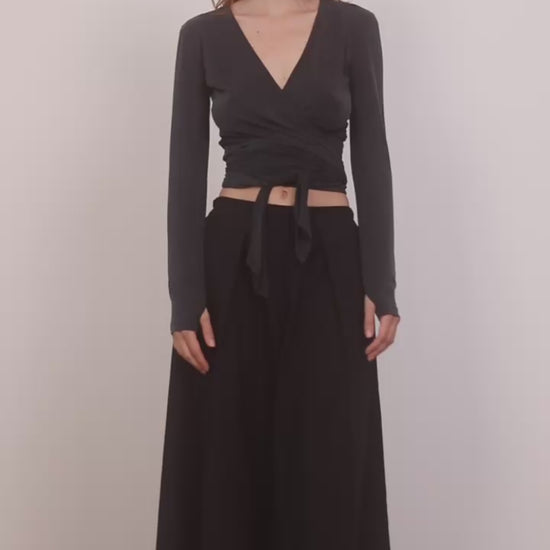 Model wearing Multiway Cupro Wrap Top in Slate Black paired with a flowy black skirt on a neutral background.