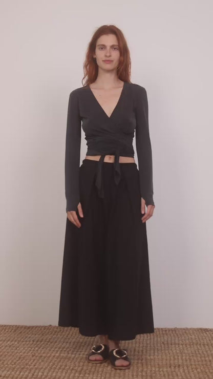 Model wearing Multiway Cupro Wrap Top in Slate Black paired with a flowy black skirt on a neutral background.
