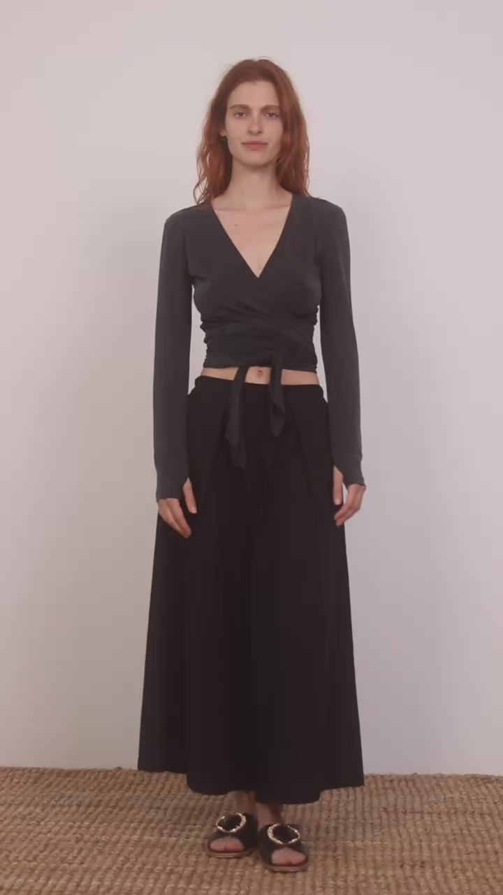 Model wearing Multiway Cupro Wrap Top in Slate Black paired with a flowy black skirt on a neutral background.