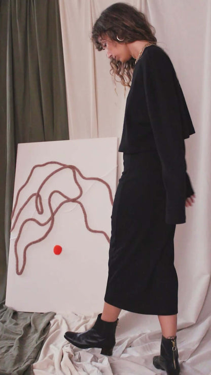 Model wearing a black organic cotton long sleeve crop top with a skirt, showcasing minimalist style and eco-friendly fashion.