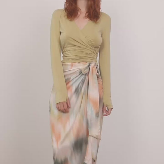 Model wearing a Multiway Cupro Wrap Top in Soft Olive paired with a colorful wrap skirt.