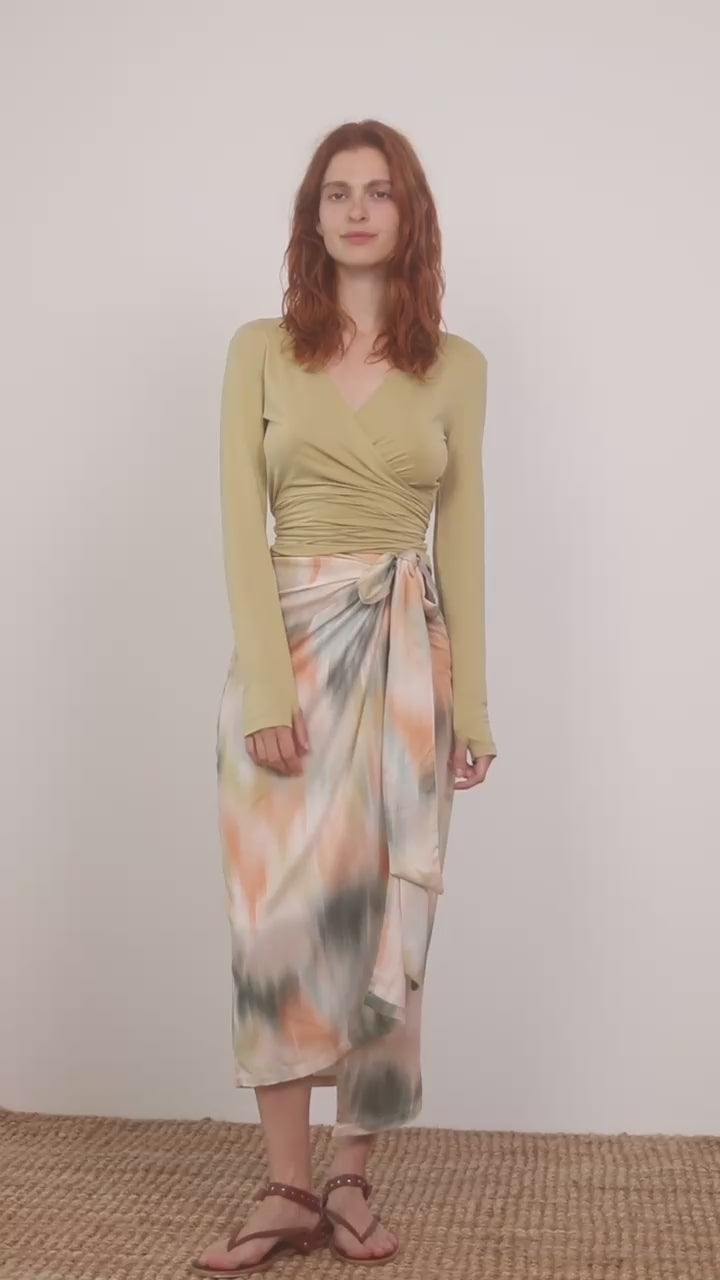 Model wearing a Multiway Cupro Wrap Top in Soft Olive paired with a colorful wrap skirt.