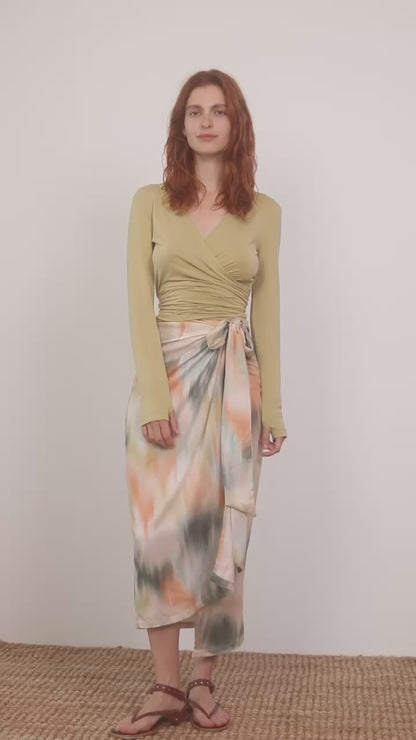 Model wearing a Multiway Cupro Wrap Top in Soft Olive paired with a colorful wrap skirt.