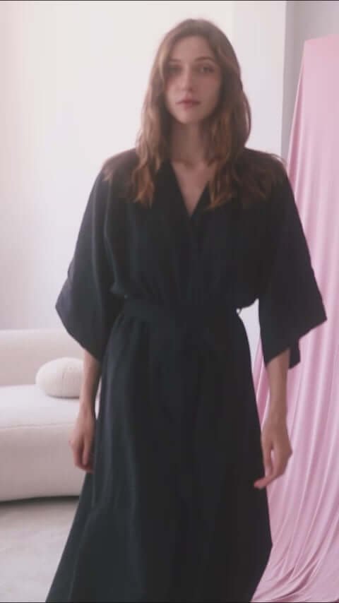 Model wearing a black kimono jumpsuit with a wrap top and belt, showcasing its elegant design and relaxed fit.