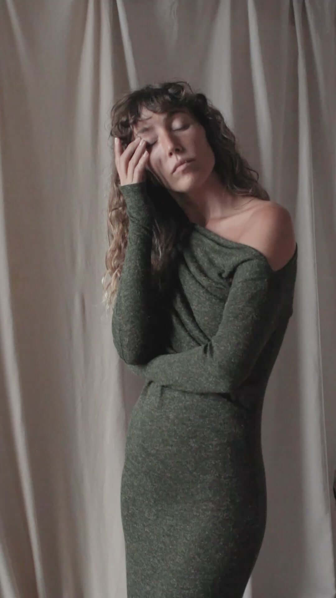 Model in a green Recycled Jersey Drape Midi Dress featuring a draped neckline and thumb holes.