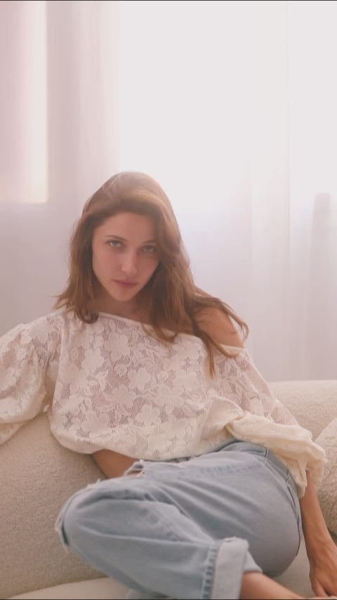 Model wearing a lace boho blouse with balloon sleeves, styled with casual jeans, in a softly lit setting.