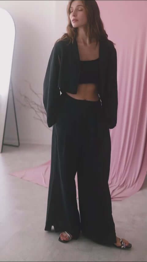 Model wearing a black crop jacket with wide trousers, showcasing modern style and comfort.