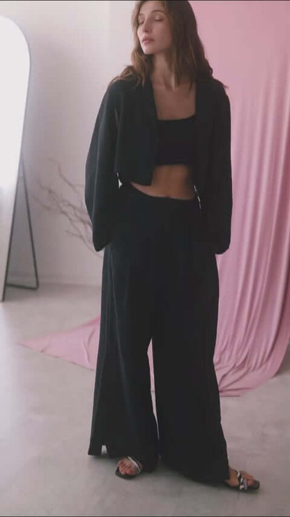 Model wearing a black crop jacket with wide trousers, showcasing modern style and comfort.