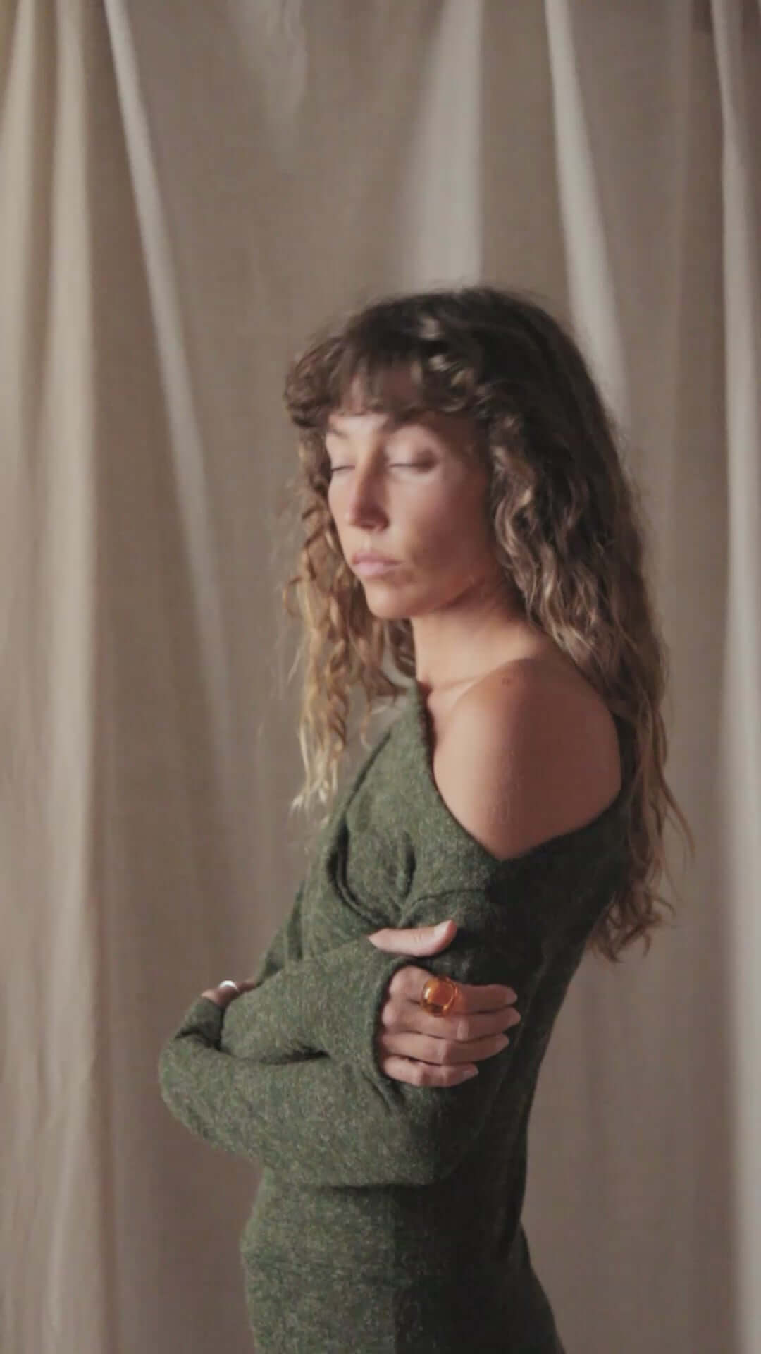Model wearing an olive green recycled jersey drape bodysuit with long sleeves and a draped neckline.